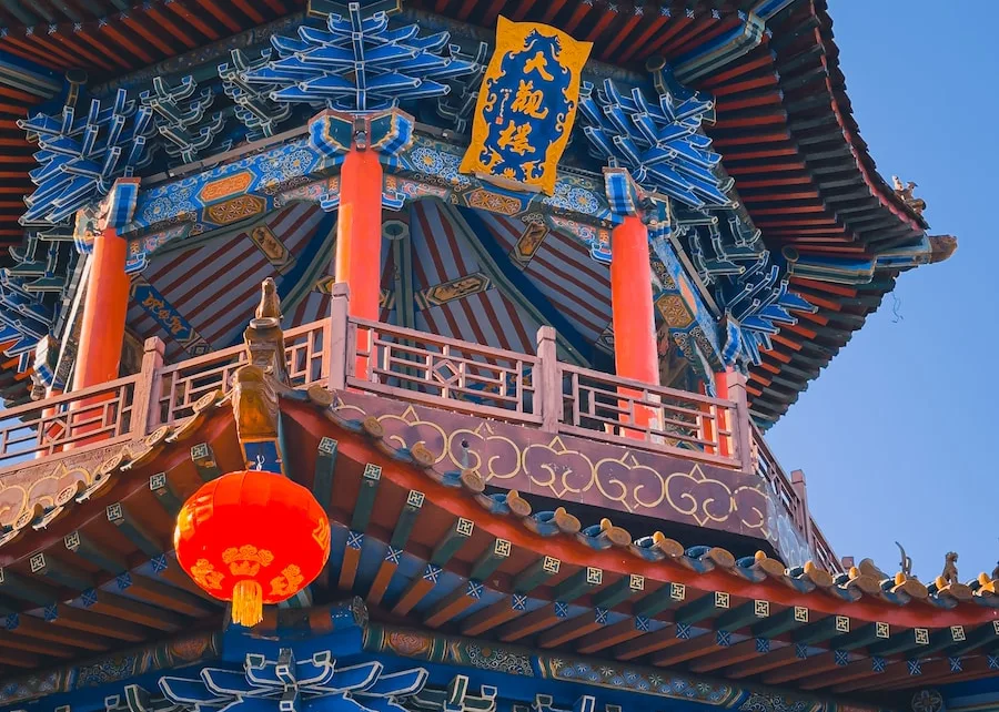 a tall tower with a red lantern hanging from it's side